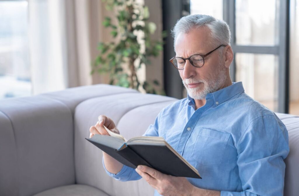 A senior is reading a book, enjoying some quiet time, while sitting on a couch in independent living.