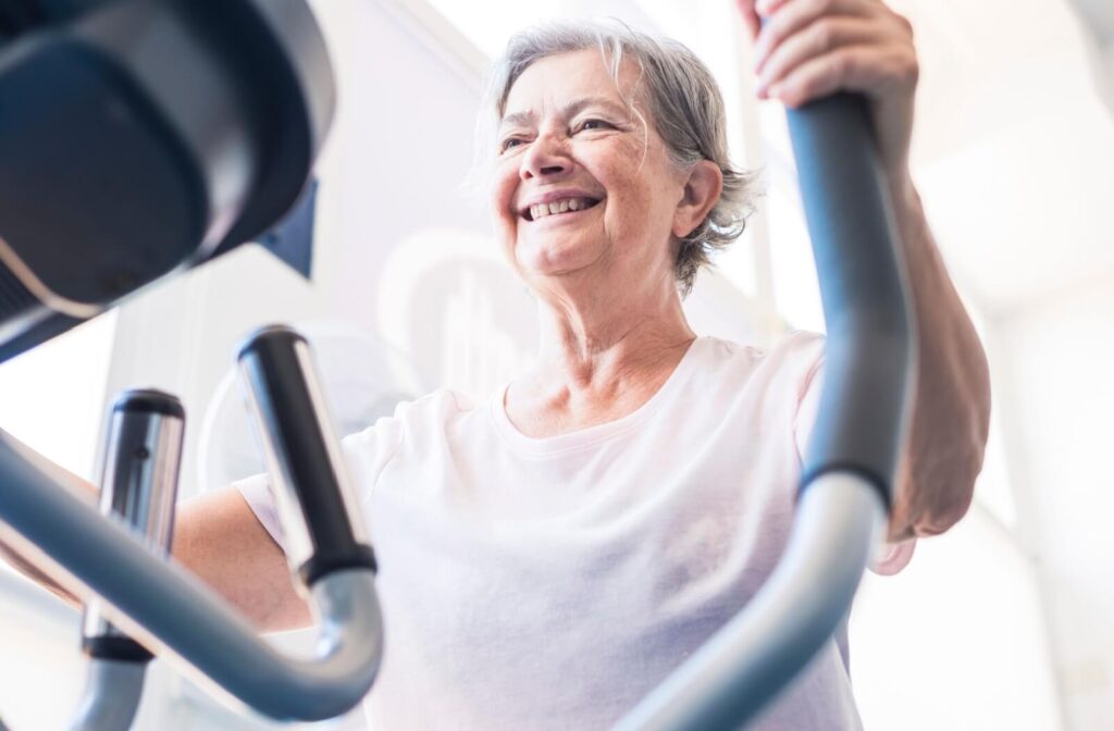 An older adult grins while using an automatic stair-climbing machine during a cardio exercise class