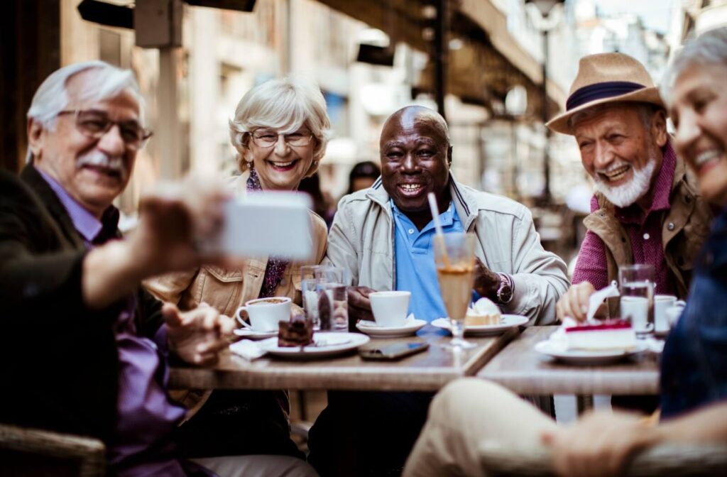 group of seniors sitting together and looking at a phone while smiling