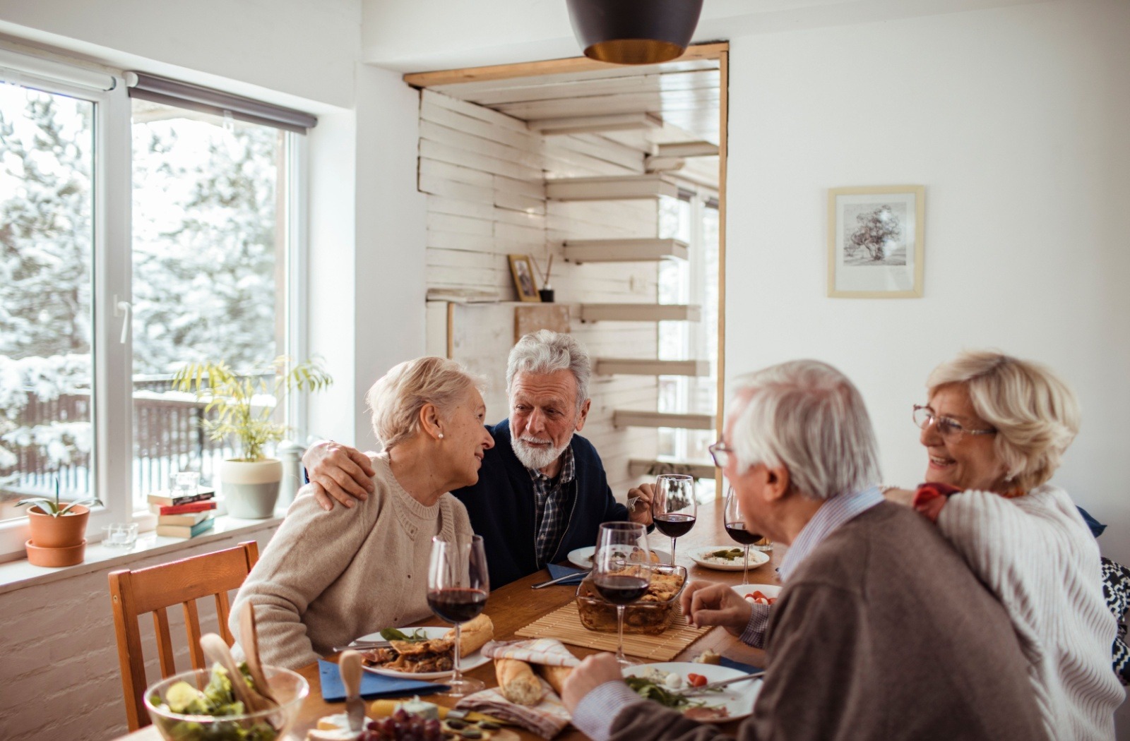 A group of senior friends smile as they enjoy a meal together.
