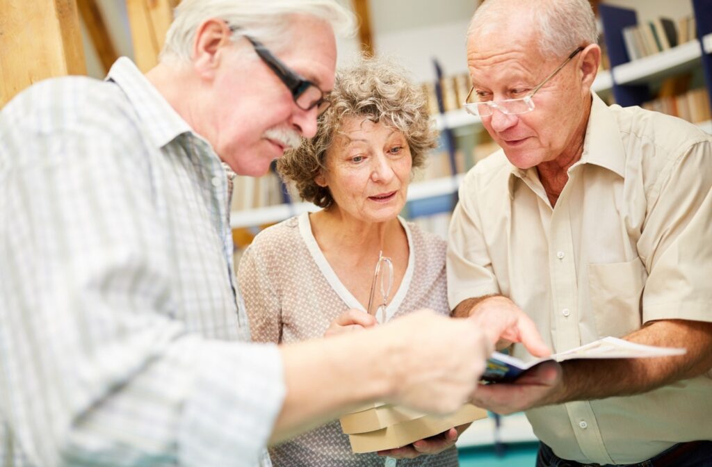 A group of seniors flip through books together in a library